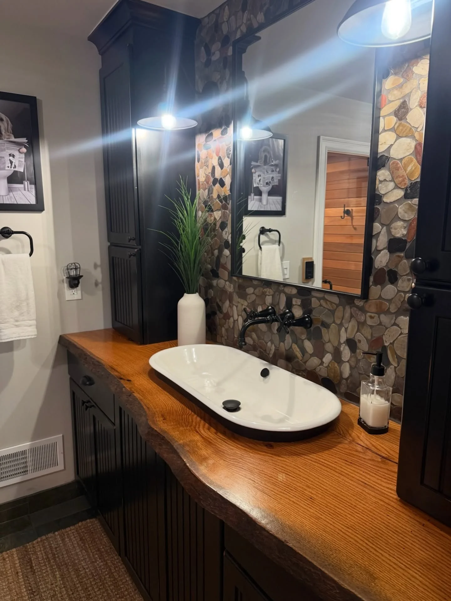 Bathroom vanity with wood countertop, white vessel sink, stacked stone wall, and recessed lighting
