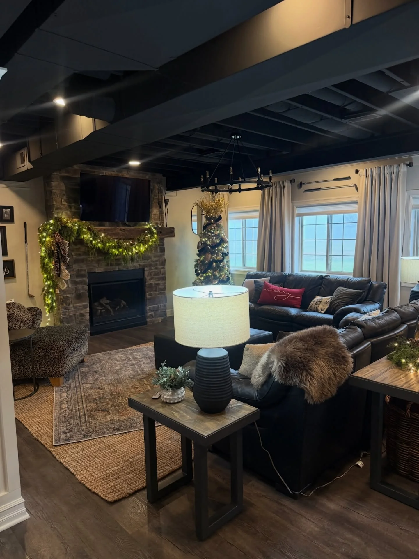 Finished basement with exposed beams, fireplace, hardwood floors, and leather seating