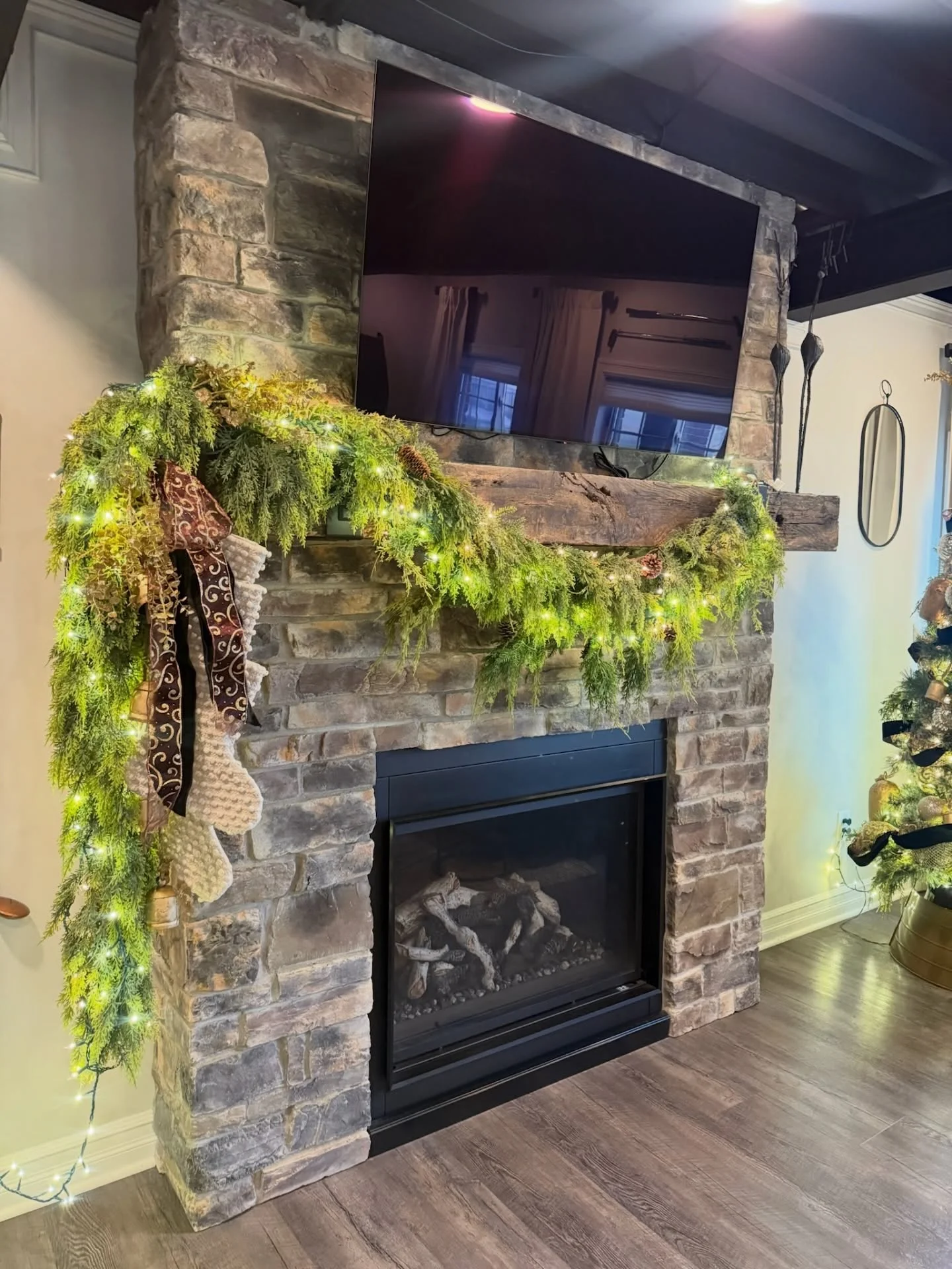 Stacked stone fireplace with timber mantel, black metal insert, and accent lighting in finished basement
