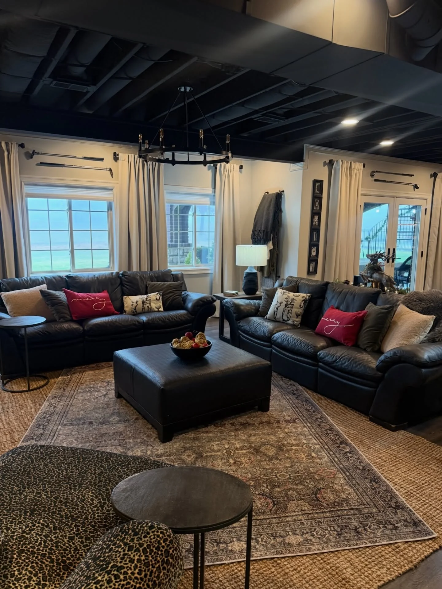 Finished basement with black ceiling beams, drywall, recessed lighting, and leather furniture arrangement