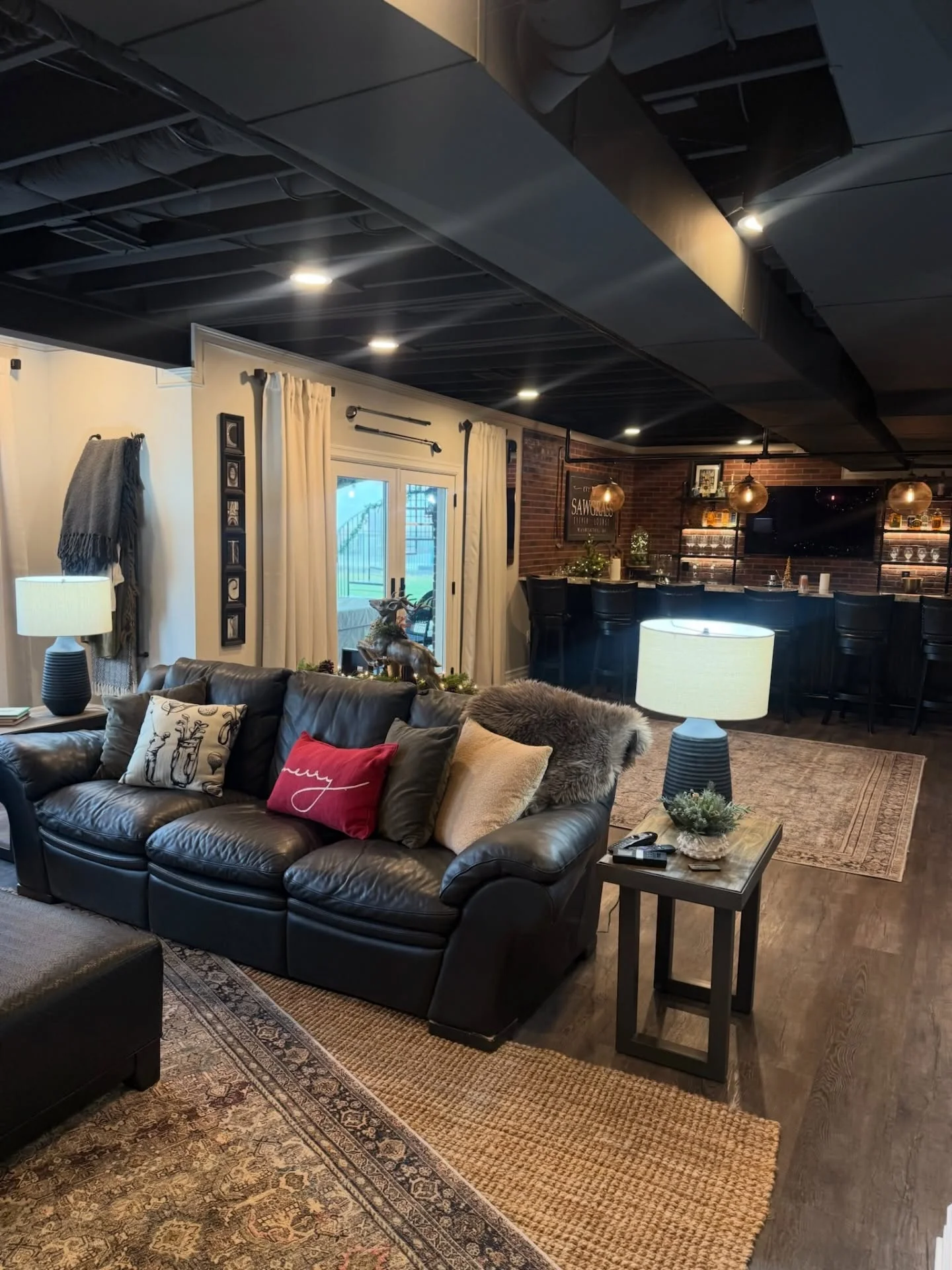 Finished basement with black ceiling, brick bar, leather seating, and recessed lighting